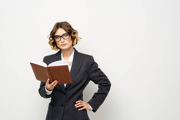 Mujer de negocios en un traje clásico con un cuaderno en la mano y gafas en la cara Copiar espacio - Foto, imagen