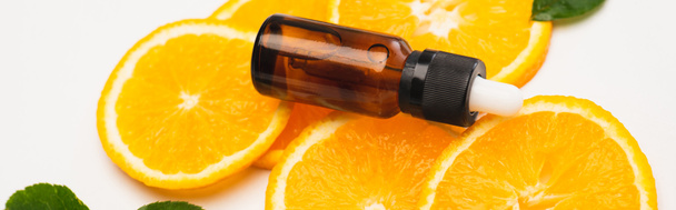 orange slices with bottle of citrus essence on white surface, banner - Foto, afbeelding