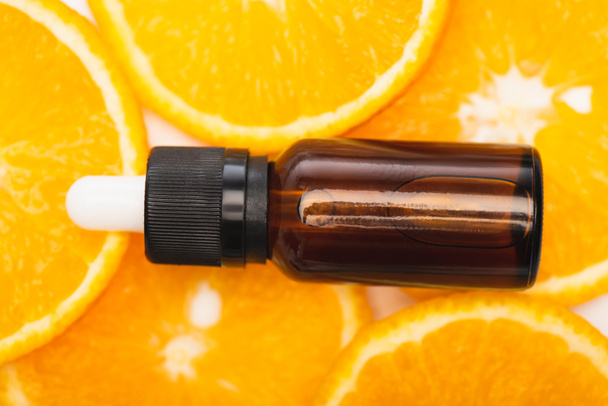 close up view of bottle with citrus essential oil on juicy, fresh orange slices, top view - Foto, Imagem