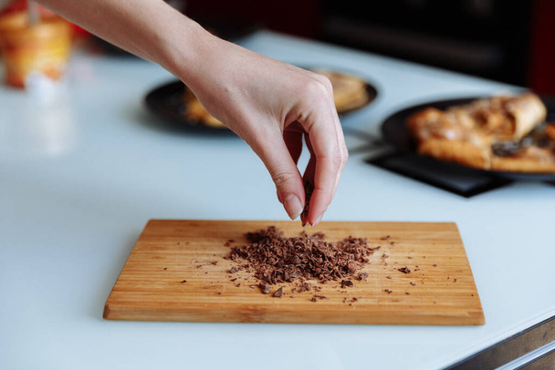 La mano del chef pastelero con chocolate rallado. Voy a espolvorear el pastel - Foto, imagen
