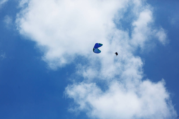 Parapente azul volando hacia el cielo con nubes en un día soleado - Foto, Imagen