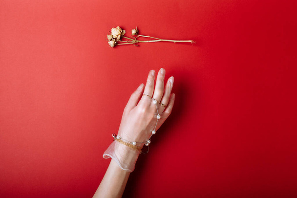 Fashion art hand woman in the glove protection against COVID-19 with Jewelry isolated on red background - Fotó, kép
