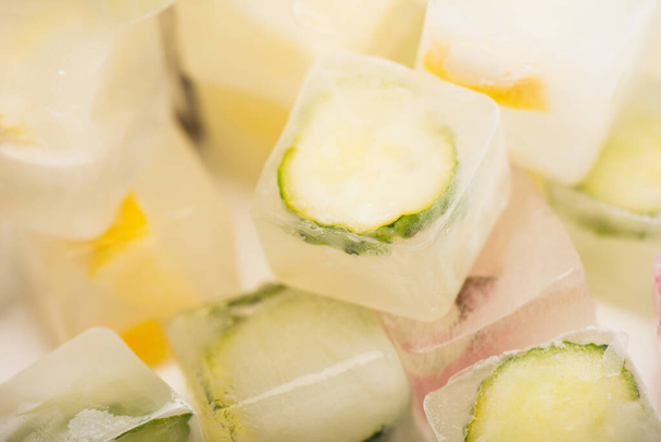 vista de perto de refrescante vegetais e frutas cubos de gelo sobre fundo branco desfocado  - Foto, Imagem