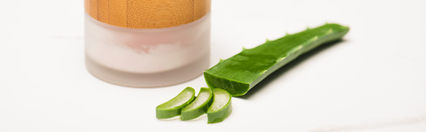 container of natural homemade cosmetic cream near cut aloe vera leaf and slices on white, banner - Photo, Image