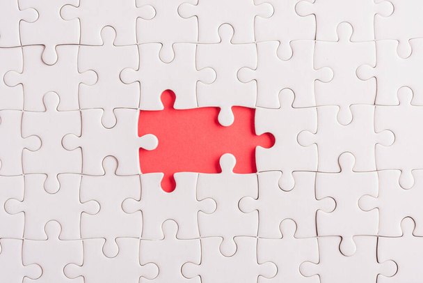 Top view flat lay of paper plain white jigsaw puzzle game texture incomplete or missing piece, studio shot on a red background, quiz calculation concept - 写真・画像