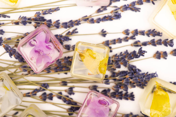 top view of floral and fruit ice cubes and lavender twigs on white surface - Fotó, kép