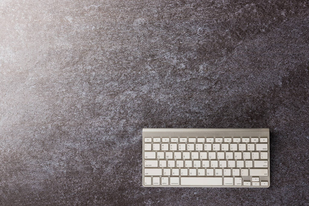 Top view flat lay of a modern white computer keyboard on office desk concrete background with copy space for text - 写真・画像