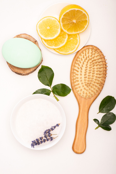 top view of brush, bowl with lavender, sliced lemon, soap, and rose leaves on white - Fotografie, Obrázek