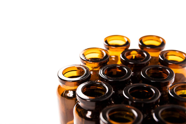 Many empty brown glass medical bottles isolated on a white background. The course of treatment is completed. Mass vaccination. Capacities for tablets. Close-up. Production of containers. - Photo, Image