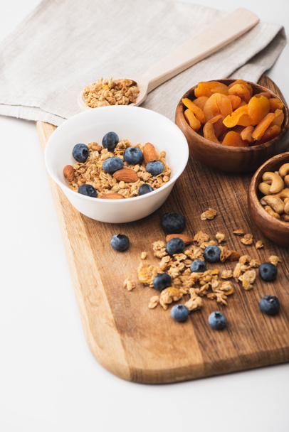 delicious granola with nuts,dried apricots and blueberry on wooden board on white background - Foto, Imagem
