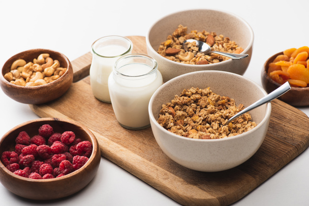 delicious granola with nuts, fruits and yogurt on wooden board on white background - Photo, Image