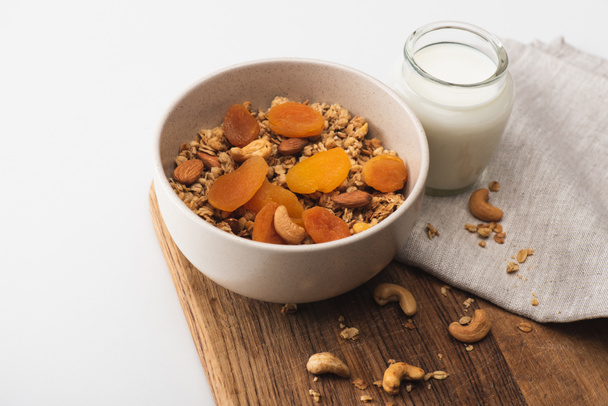 delicious granola with nuts, dried apricots and yogurt on wooden board on white background - Photo, Image