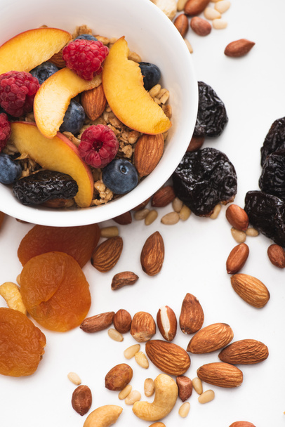 leckeres Müsli mit Nüssen, Beeren und Früchten in einer Schüssel auf weiß - Foto, Bild
