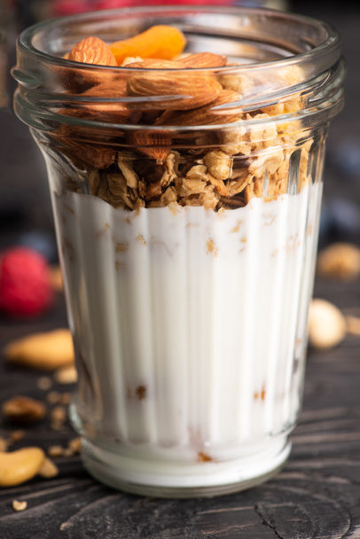 closeup of delicious granola with dried apricots, nuts and yogurt in glass cup - Photo, Image