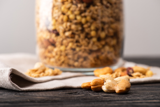 blurred delicious granola in glass gar on napkin and nuts - Fotó, kép