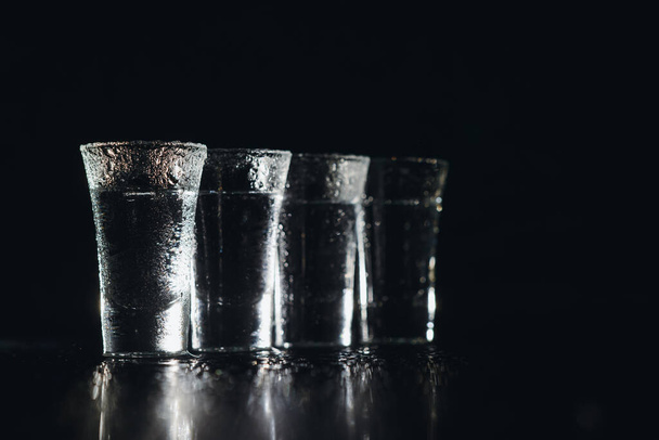 Vodka. Shots, glasses with vodka with ice .Dark background. Copy space .Selective focus - 写真・画像