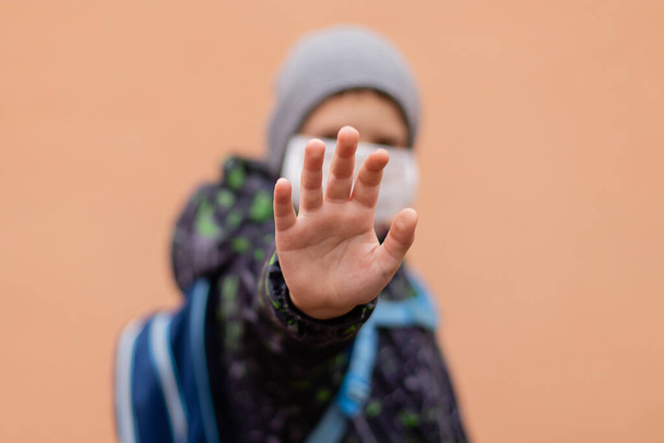 Un colegial con una máscara protectora muestra su mano PARADA - Foto, Imagen