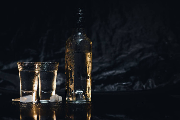 Vodka. Colpi, bicchieri con vodka con ghiaccio. Sfondo scuro. Copia spazio. Focus selettivo - Foto, immagini