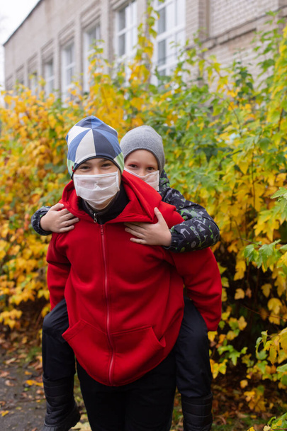 the schoolchildren in protective masks in the street - Photo, Image
