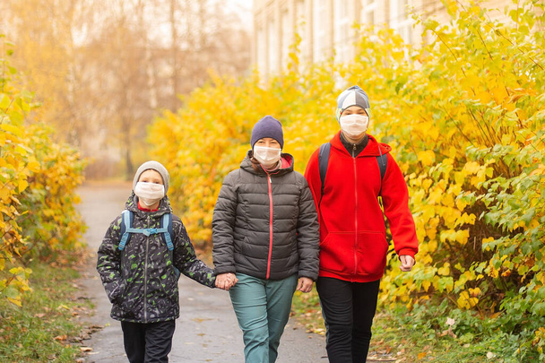 the mom with two sons in the street wearing protective masks, walking - Foto, immagini