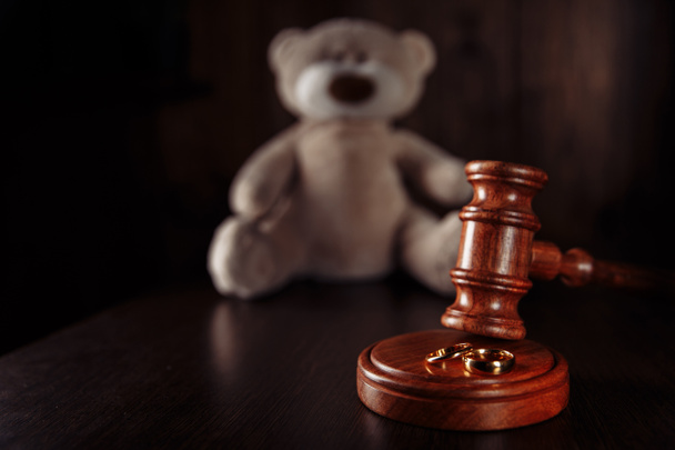 Divorce in family with children. Wooden gavel, rings and teddy bear - Photo, Image