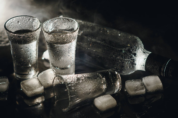 Vodka. Shots, glasses with vodka with ice .Dark background. Copy space .Selective focus - Foto, Bild