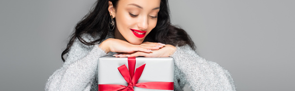 femme heureuse avec des lèvres rouges regardant boîte cadeau isolé sur gris, bannière - Photo, image