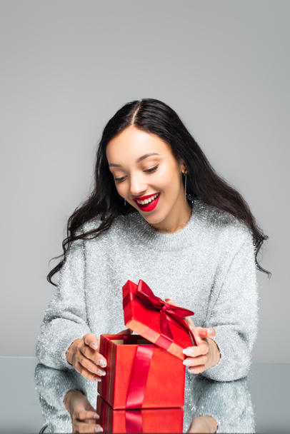 excited woman with red lips looking at present isolated on grey - Photo, Image