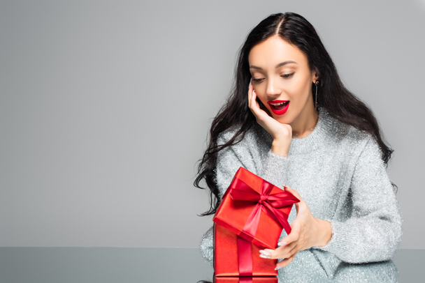 surprised woman with red lips looking at present isolated on grey - Photo, image