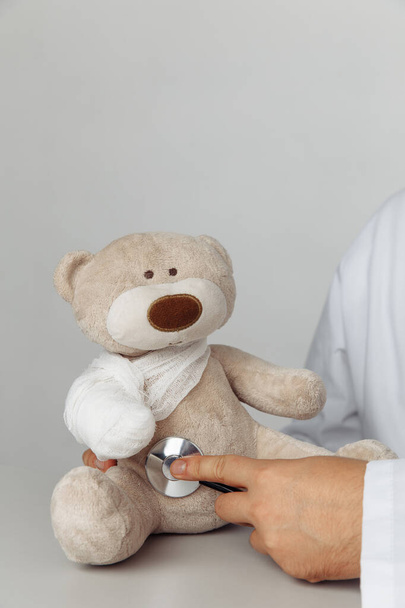 Concetto pediatrico. Medici mano con stetoscopio e orsacchiotto con benda - Foto, immagini