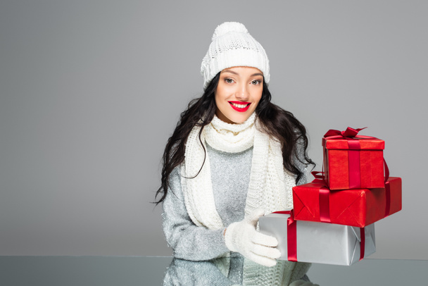 cheerful woman in winter outfit holding presents isolated on grey - Φωτογραφία, εικόνα