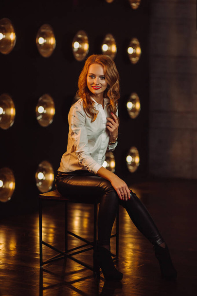 Business Woman in a white shirt against the background of burning lamps in the interior of a dark Studio.Model with long hair and red lipstick. - Valokuva, kuva