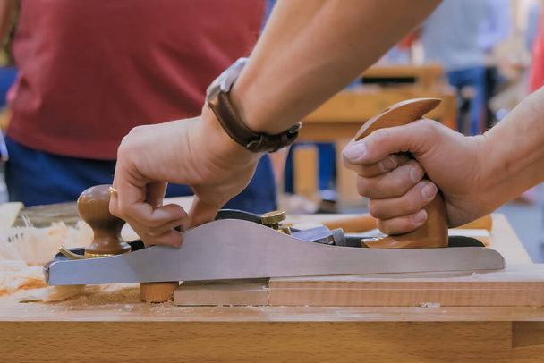 Carpintero usando portavoz o plano para dar forma al tablero de madera - vista lateral de cerca - Foto, Imagen