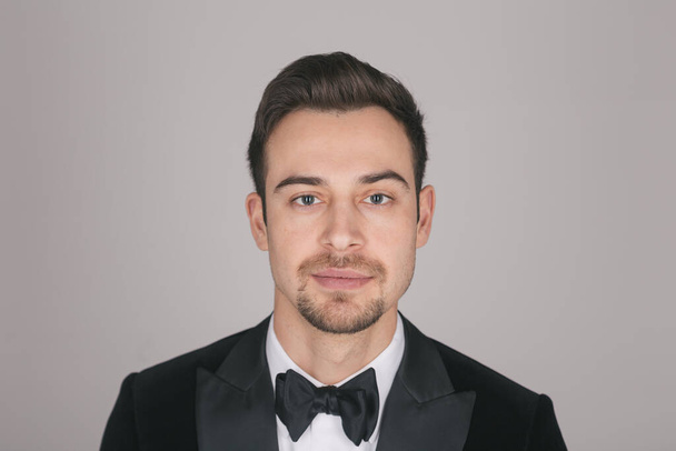 Studio portrait of a young caucasian man in a tuxedo, seriously looking at the camera, against plain studio background - Photo, Image