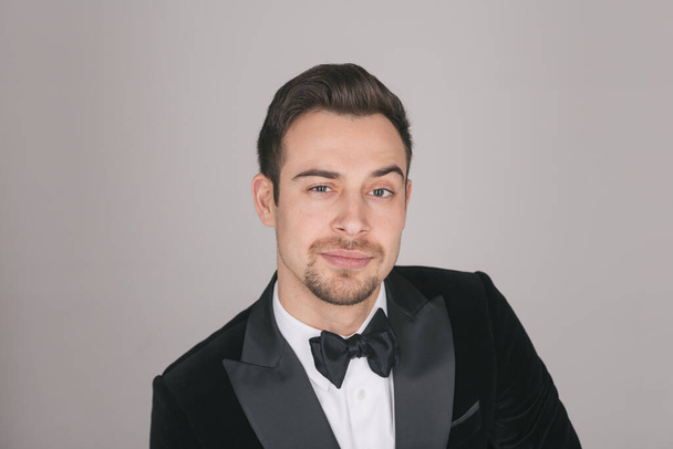 Studio portrait of a young caucasian man in a tuxedo, looking at the camera, against plain studio background - Photo, Image