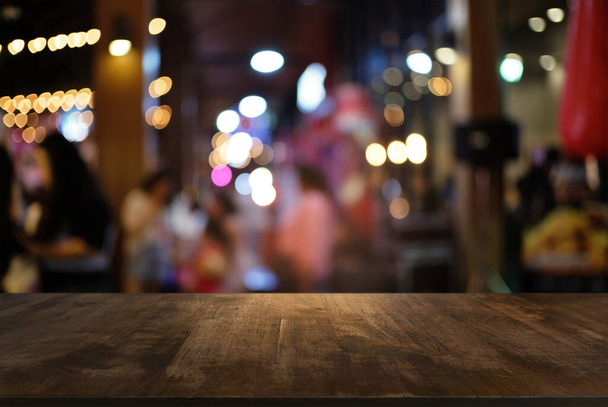 Tampo de mesa de madeira vazio e borrão de fundo do mercado noturno / foco seletivo. - Foto, Imagem
