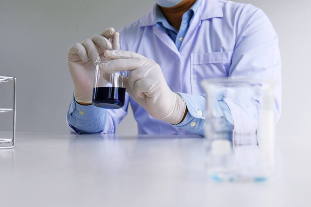 Badacz laboratoryjny męski lub naukowy wykonuje badania z niebieskim płynem w laboratorium. Koncepcja sprzętu laboratoryjnego i eksperymentów naukowych - Zdjęcie, obraz