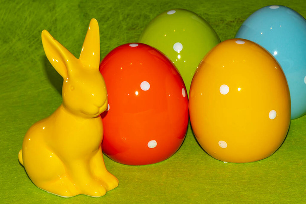 Барвисті керамічні великодні яйця та великодній кролик перед зеленим тлом
 - Фото, зображення