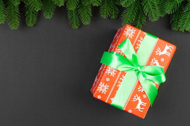 Top view of fir tree branches and gift box on colorful background. Christmas time concept with empty space for your design. - Photo, Image