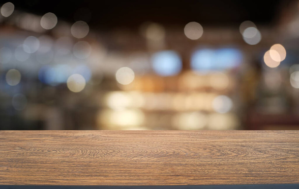 Κενό σκούρο ξύλινο τραπέζι μπροστά από αφηρημένη θολή bokeh φόντο του εστιατορίου. μπορεί να χρησιμοποιηθεί για επίδειξη ή μοντάζ τα προϊόντα σας.Mock up for space  - Φωτογραφία, εικόνα
