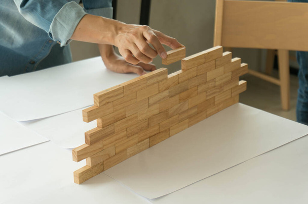 Žena v džínové košili drží bloky dřeva hra (jenga) Stavba malé cihlové zdi Rizikové koncepce. - Fotografie, Obrázek