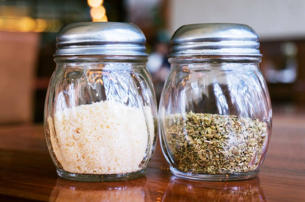 Szklanka soli serowej i pieprzniczki na drewnianym stole w restauracji. - Zdjęcie, obraz