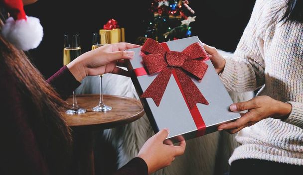 Молодая красивая женщина дарит подарок другу. Концепция празднования Рождества или Нового года - Фото, изображение