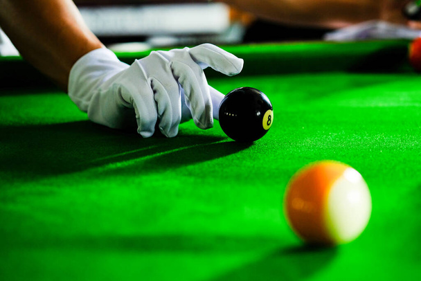 Man's hand and Cue arm playing snooker game or preparing aiming to shoot pool balls on a green billiard table. Colorful snooker balls on green frieze - Photo, Image