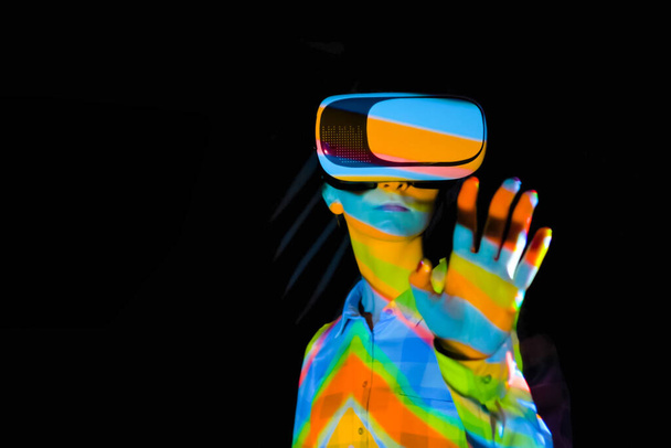Mujer joven usando auriculares de realidad virtual en la exposición interactiva oscura VR - Foto, imagen