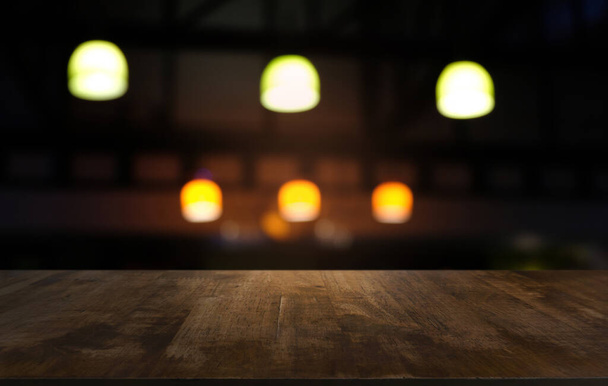 Mesa de madeira escura vazia na frente do fundo bokeh embaçado abstrato do restaurante. pode ser usado para exibir ou montar seus produtos.Preparar para o espaço - Foto, Imagem