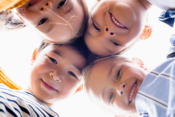 Pohja näkymä monikansallisten lasten hymyillen kameran eristetty valkoinen  - Valokuva, kuva