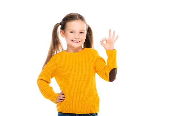 glimlachend meisje met de hand op de heup tonen oke geïsoleerd op wit - Foto, afbeelding