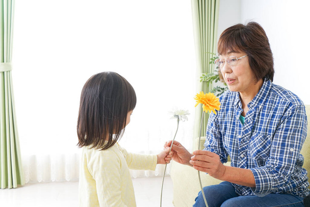 Kind geeft bloem aan gnandma - Foto, afbeelding