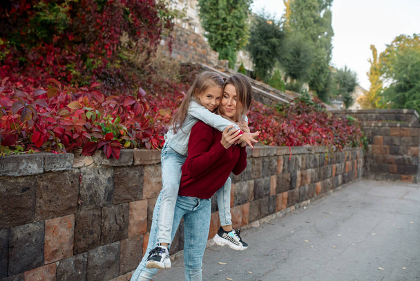 Beautiful young family mom hugs her pretty daughter on a walk in the park in autumn - Foto, Bild